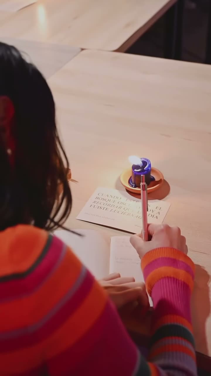 Mirona escribiendo a mano con una vela encendida sobre la mesa